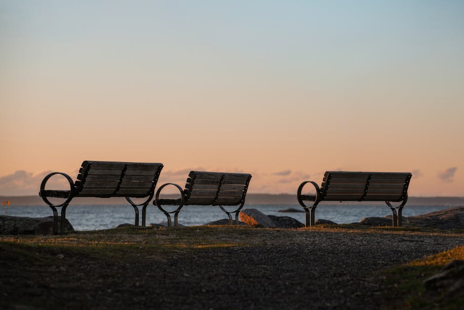 Drei leere Parkbänke mit Blick aufs Meer bei Sonnenuntergang