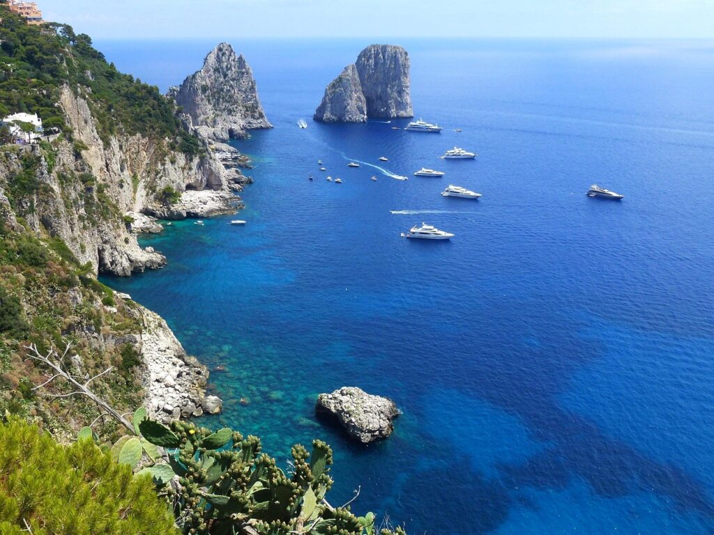 Turkusowe wody wokół Faraglioni na Capri, łodzie i kaktusy