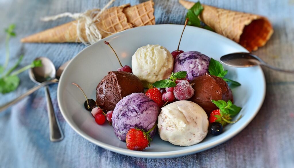 Teller mit sechs Eiskugeln verschiedener Sorten, Beeren und frischer Minze