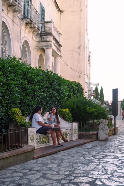 Zwei Frauen auf dekorierter Bank vor Gebäude in den Gassen von Capri
