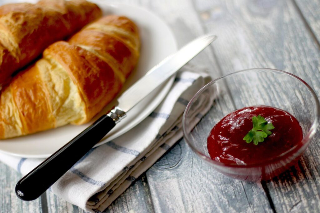 Twee verse croissants met mes en rode jam bij Capri-ontbijt