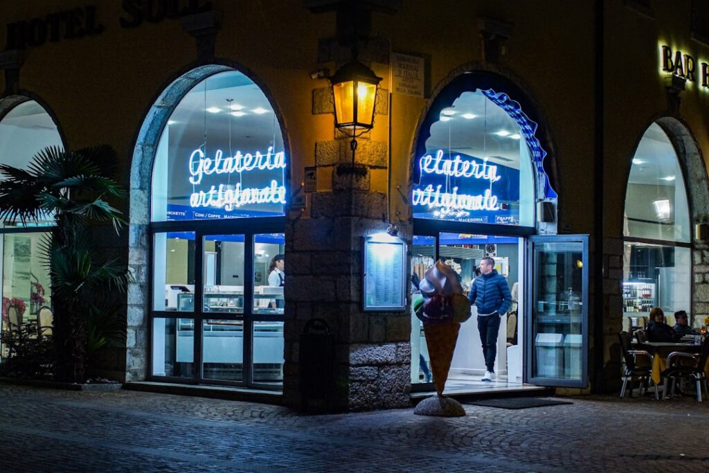 Gelateria nocturne éclairée au néon, entrée et cône géant