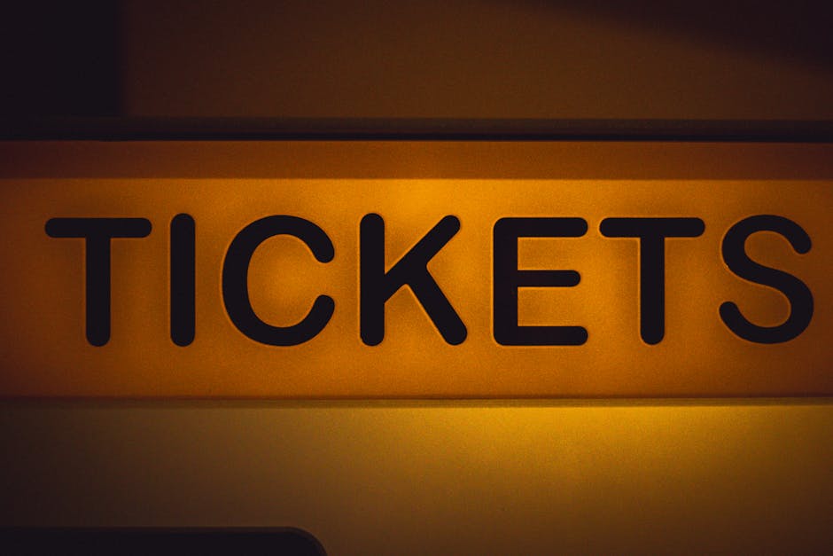Backlit yellow sign reading TICKETS in bold black letters