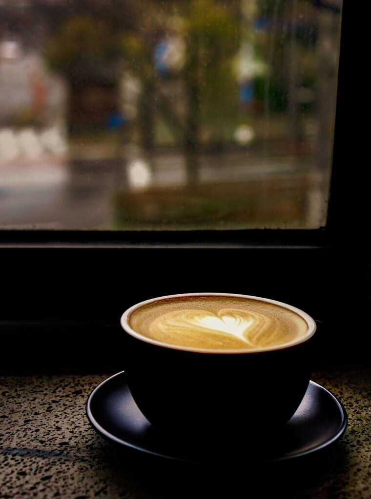 Tasse de cappuccino avec latte art posée près d'une fenêtre