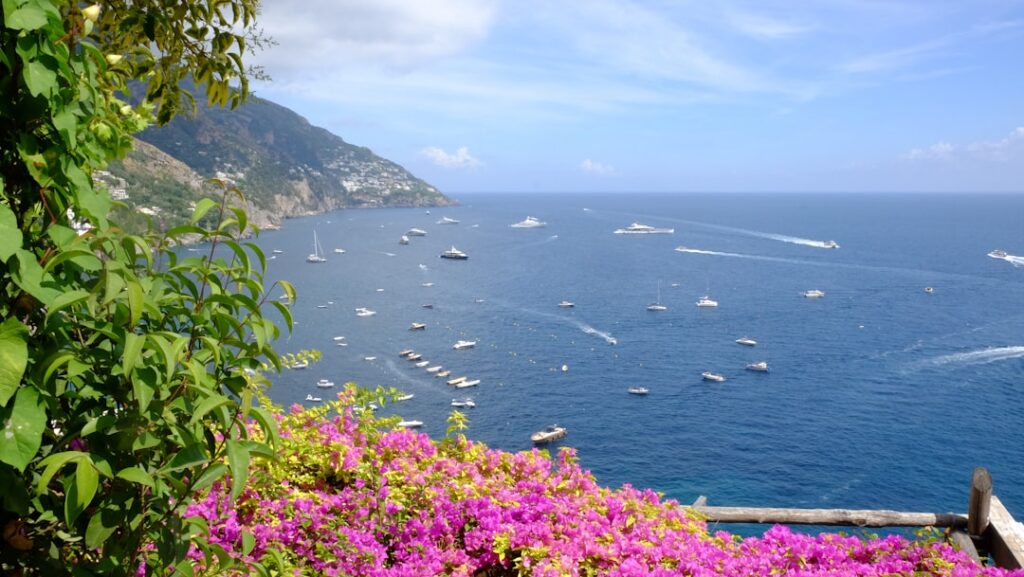 Bougainvilliers roses encadrant la mer bleue et les bateaux à Capri