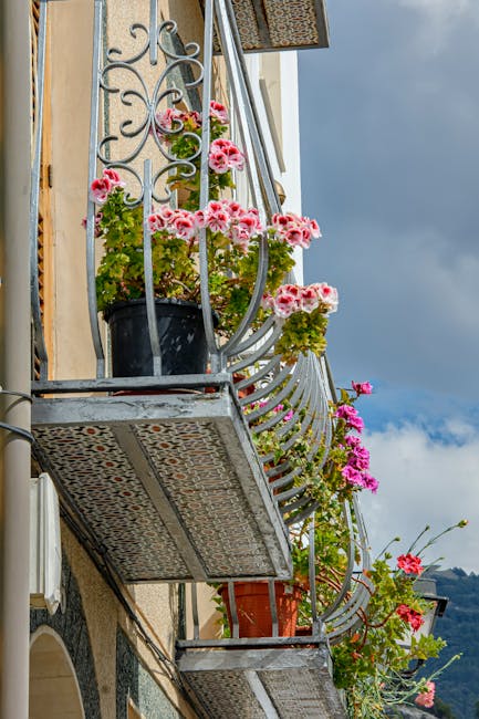 Sierlijk balkon met roze geraniums tegen een gevel