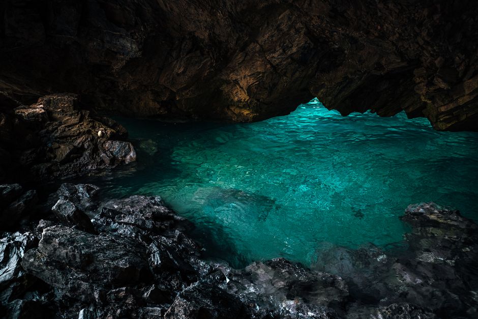Turquoise water shimmering inside a dark sea cave on Capri
