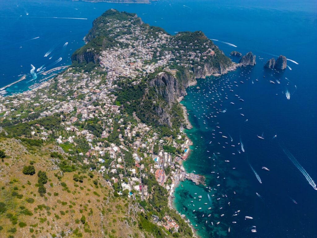 Luchtfoto van Capri met dorp, kliffen en veel boten in zee