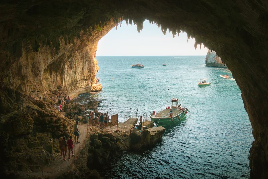 Visitors and small boats at a rocky cave entrance on Capri