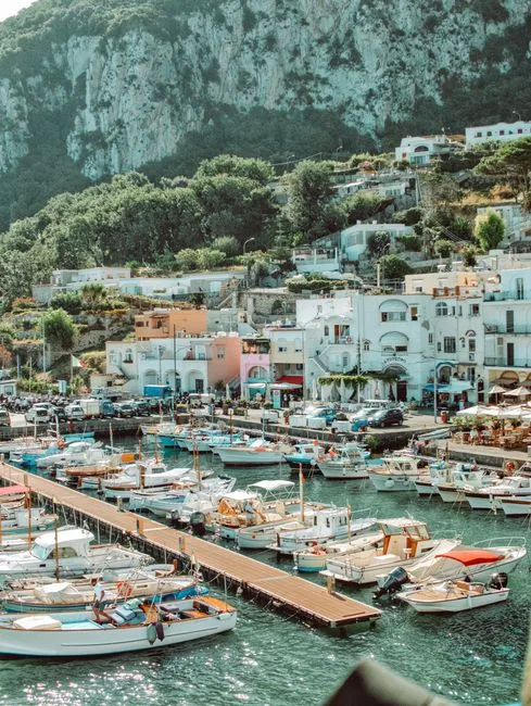 Bunte Boote im Hafen von Capri vor weißen Häusern am Hang