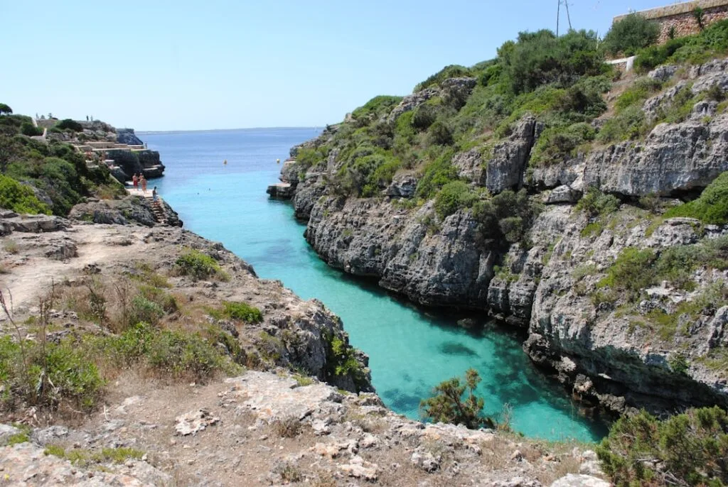 Türkisblaues Meerwasser in schmaler Felsbucht mit Vegetation oben