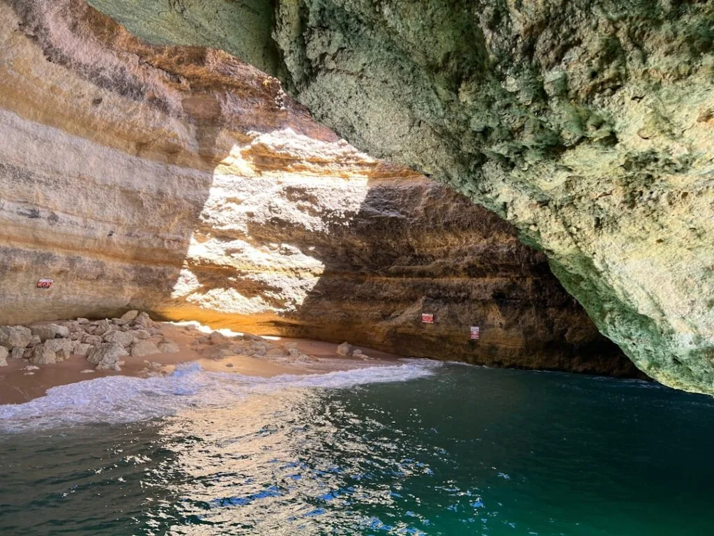 Sonnenlicht fällt auf kleinen Sandstrand in mächtiger Meereshöhle