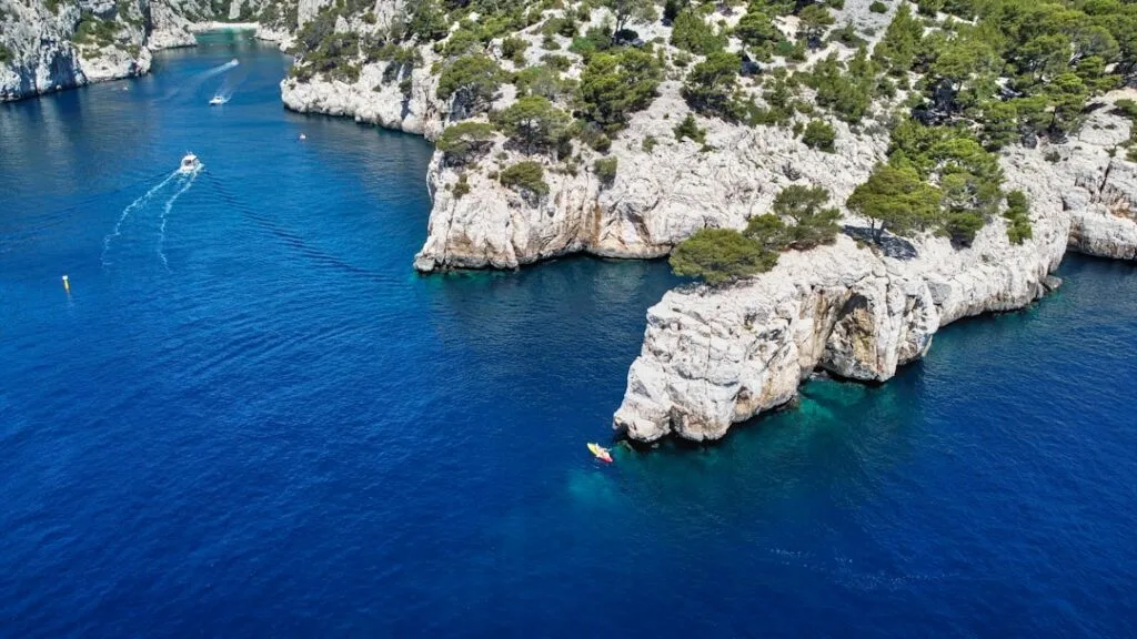 Luftaufnahme einer Felsküste mit Kajak im tiefblauen Wasser bei Capri