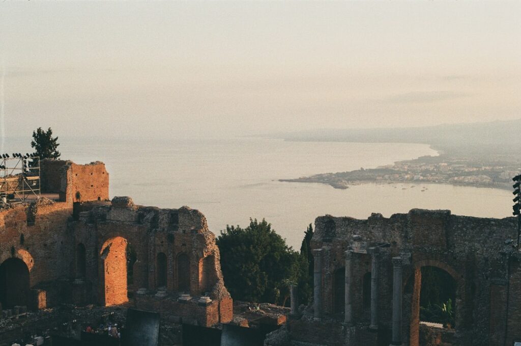 Ruines du théâtre antique de Taormina dominant la mer au coucher.