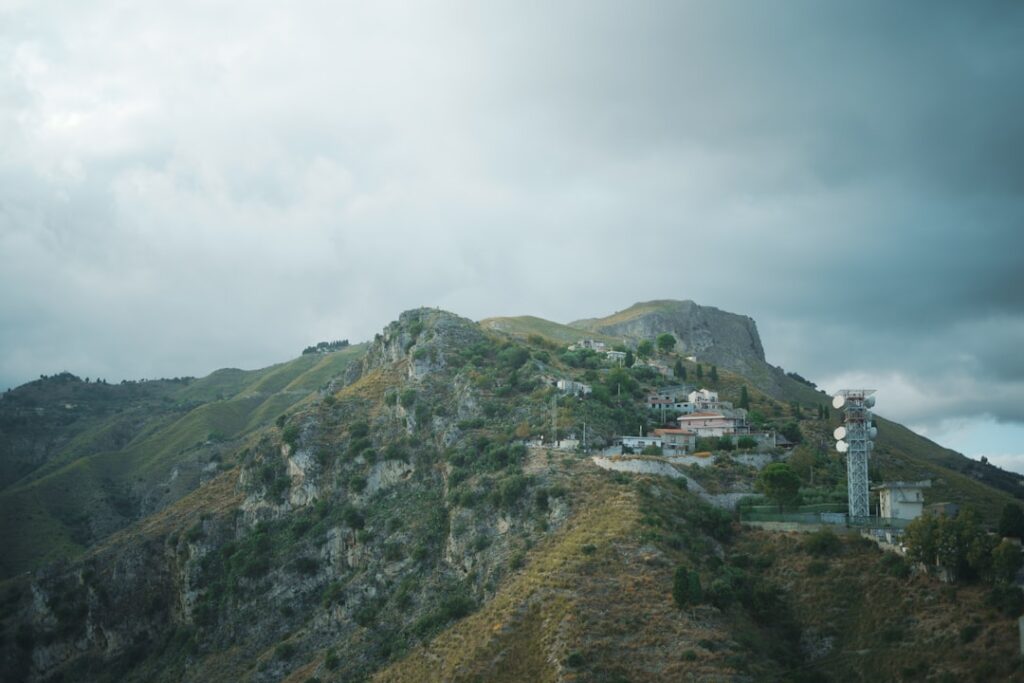 Sommet rocheux avec village et antenne de télécommunication en Sicile.