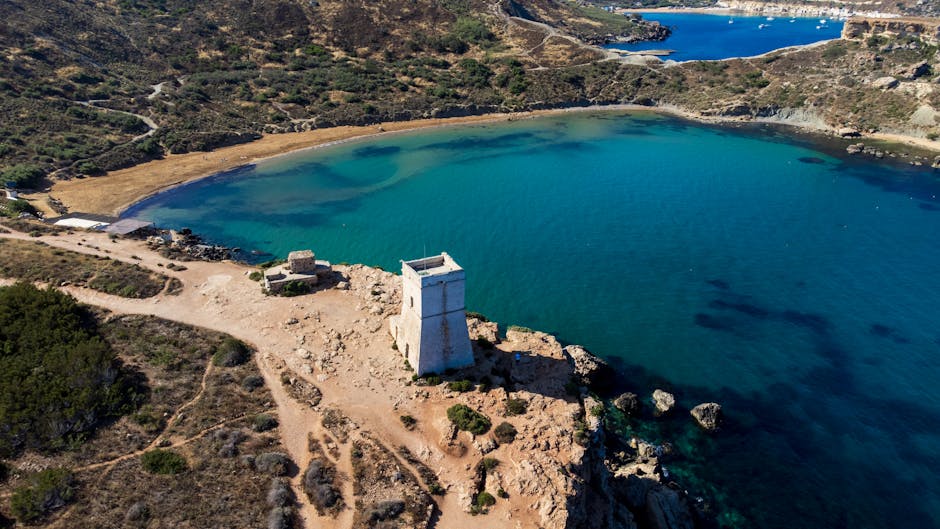 Tour côtière sur un promontoire rocheux dominant une baie turquoise en Sicile