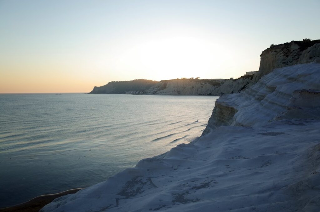 Sunset view along white Scala dei Turchi cliffs and distant coastline, Sicily