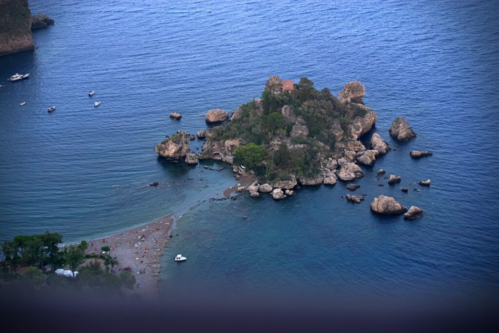 Isola rocciosa con vegetazione e casetta vicino Taormina, Sicilia