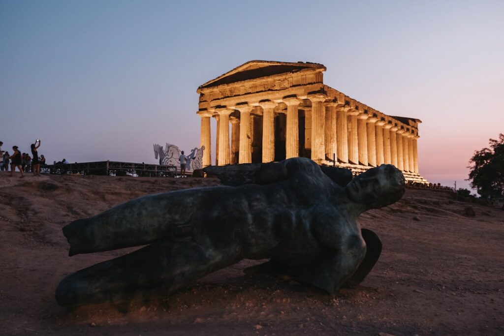 Aangestoken tempel bij avond met liggend bronsbeeld in de Vallei van de Tempels