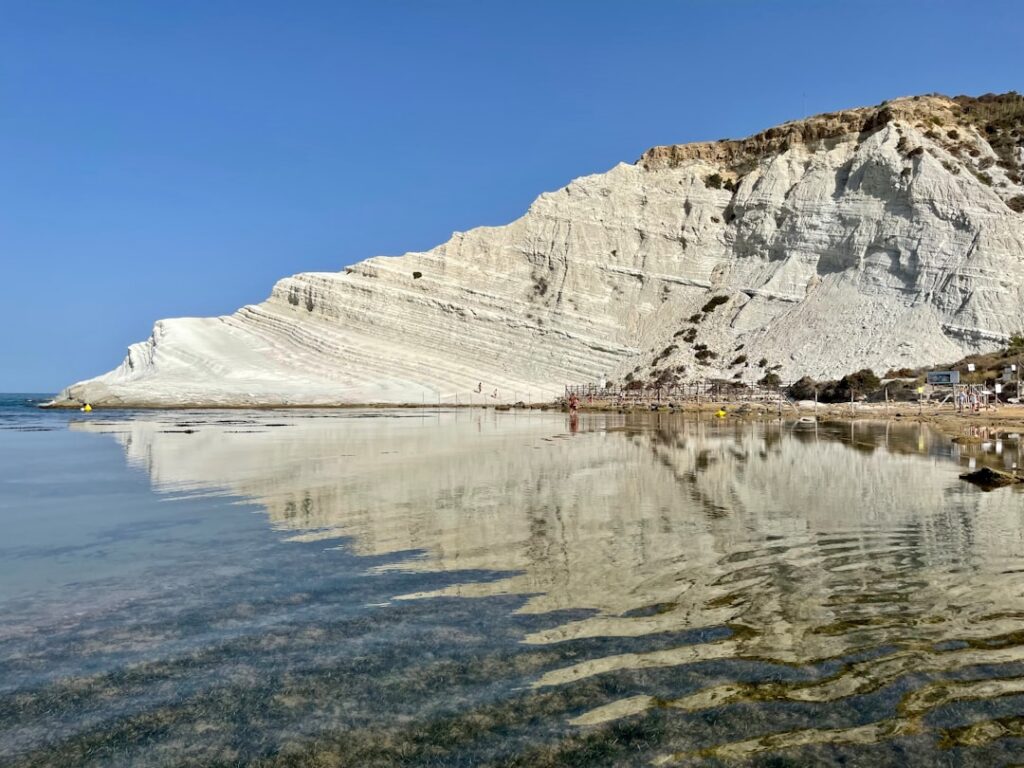 Mirrored white Scala dei Turchi cliffs reflected in tranquil shallow Sicilian water