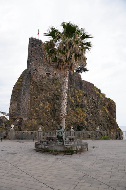 Vieux rocher fortifié avec palmier et drapeau italien sur la côte sicilienne