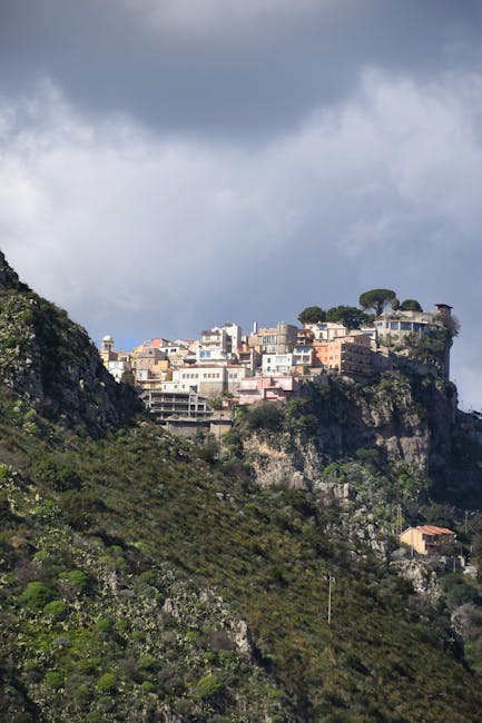 Cliffside village perched on rocky promontory above Sicilian valley