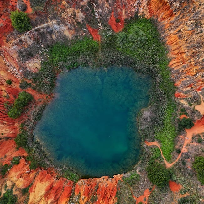 Lac circulaire bleu turquoise entouré d'argiles rouges et végétation