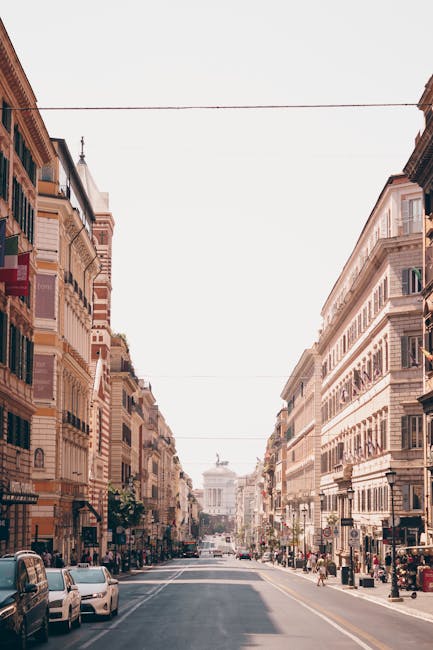 Large avenue bordée d'immeubles classiques avec monument au loin