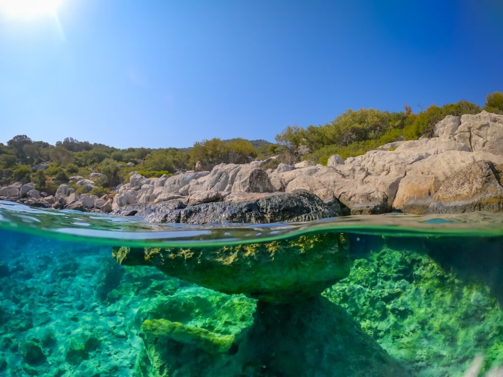Veduta a metà acqua di costa rocciosa e fondale trasparente in Sicilia
