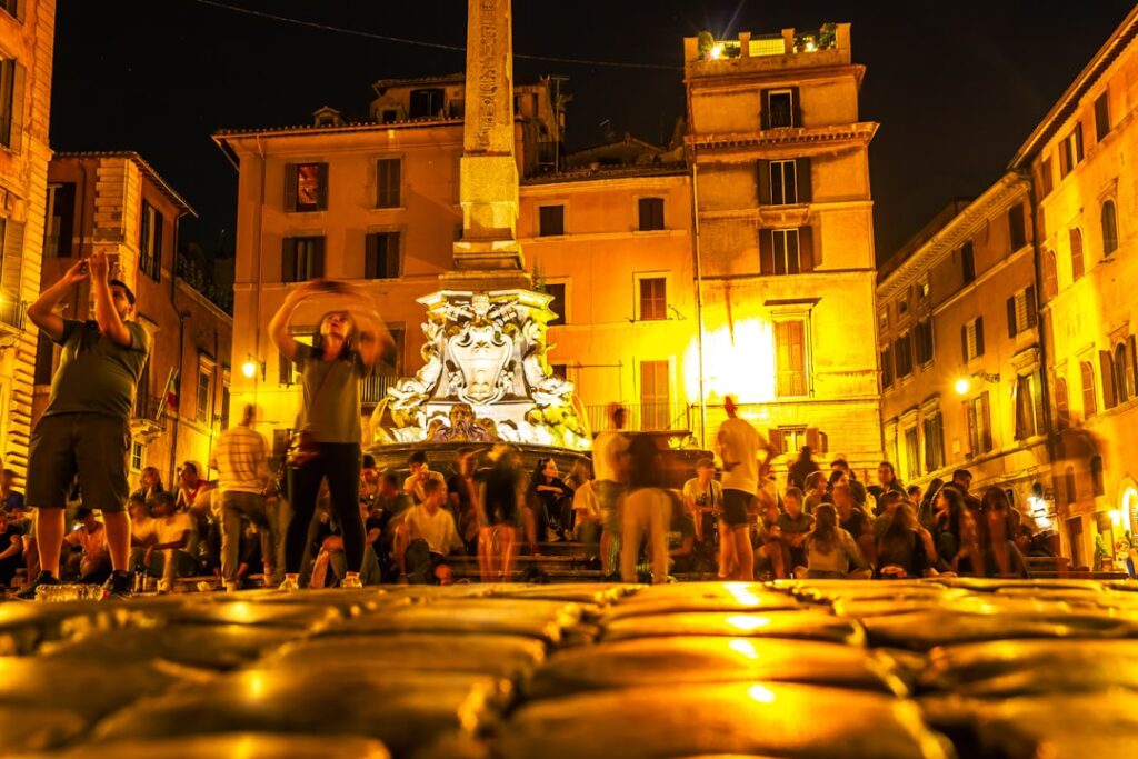 Evening Sicilian piazza glowing with fountain lights and moving crowds