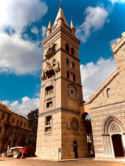 Tall Messina cathedral bell tower with astronomical clock against blue sky