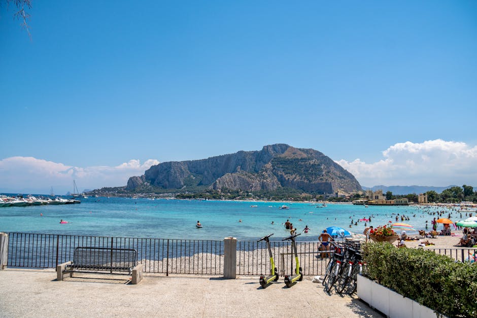 Colorful beach umbrellas, scooters and Monte Pellegrino across Sicilian bay