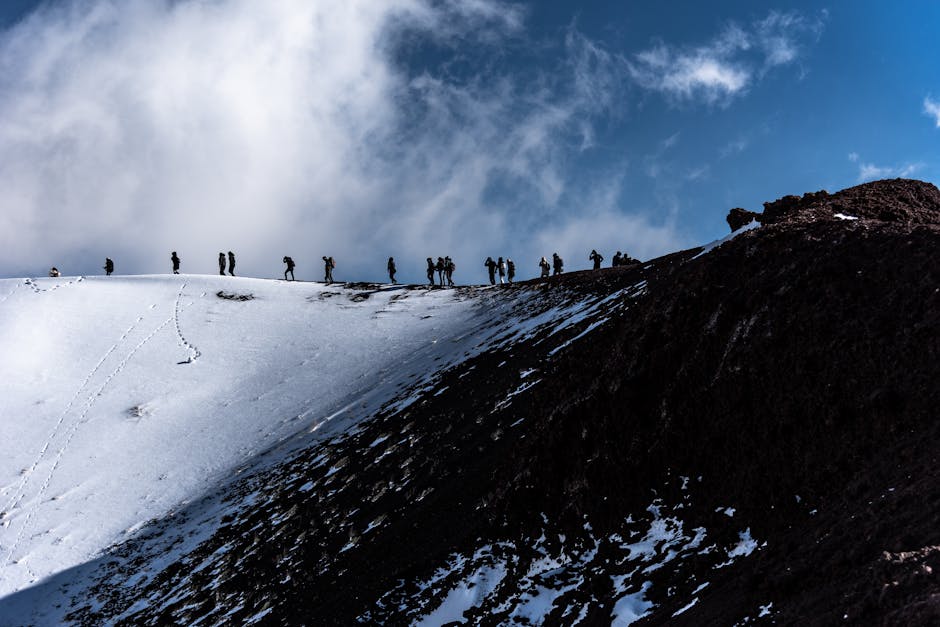 Silhouetten von Wanderern am schneebedeckten Kraterrand des Ätna in Sizilien