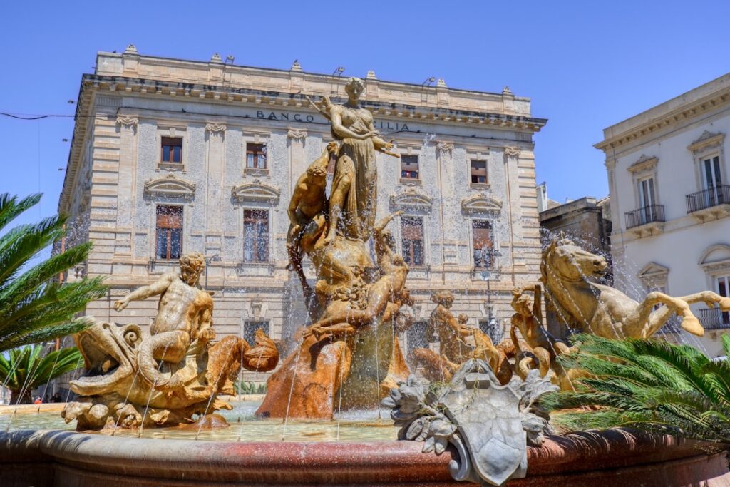 Fontaine sculptée baroque animée par jets d'eau, place urbaine en Sicile