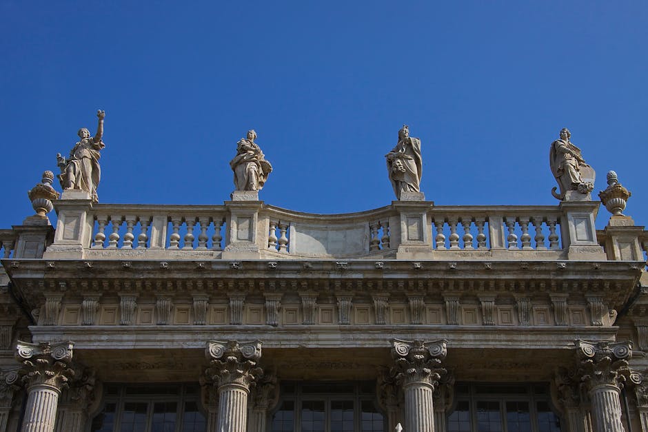 Balustrade sculptée et statues baroques sur un fronton, ciel bleu