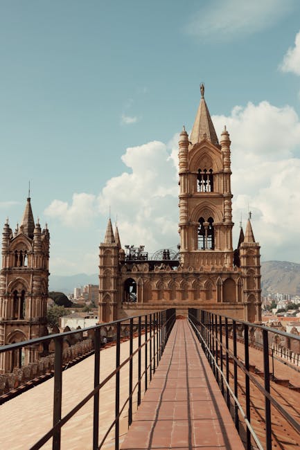 Roof walkway leading to Palermo Cathedral bell towers under pale blue sky
