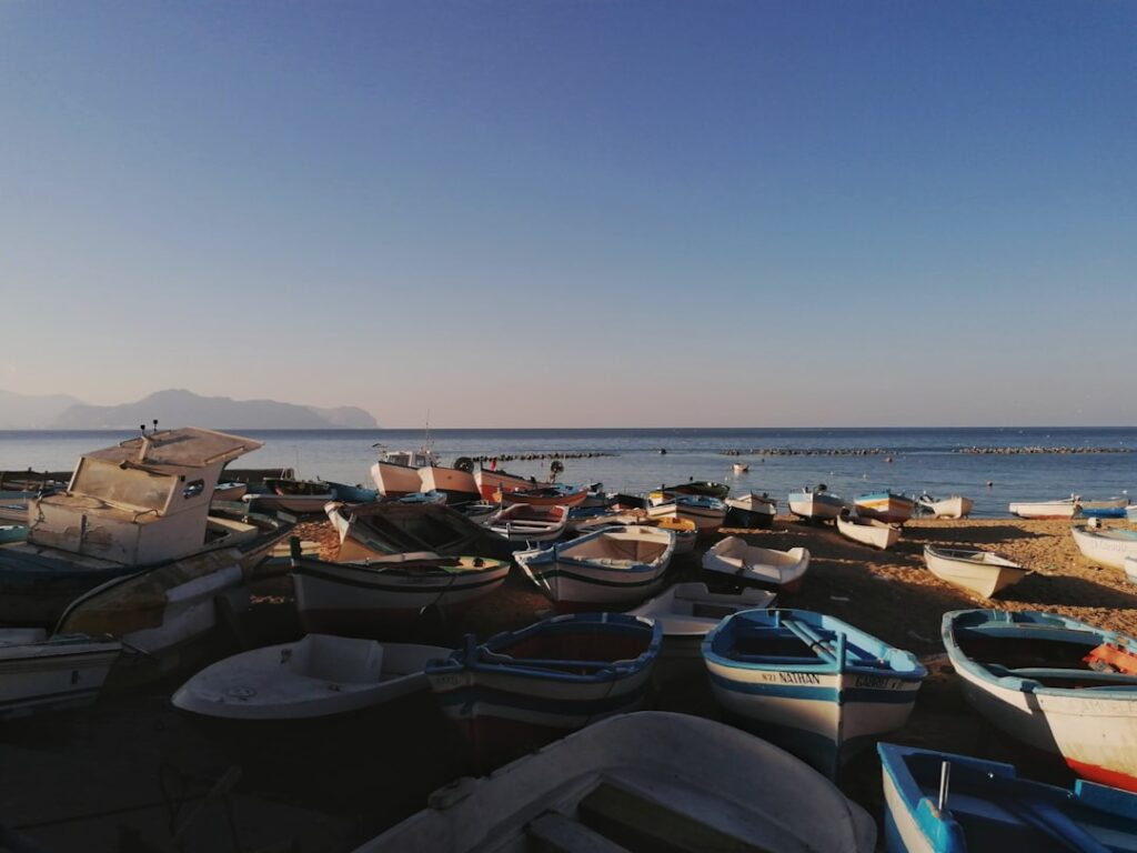 Wiele kolorowych łodzi rybackich rozsypanych na piaszczystej plaży Sycylii