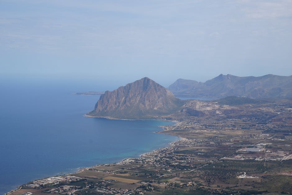 Küstenpanorama mit markantem Felsen und Siedlungen an Siziliens Küste