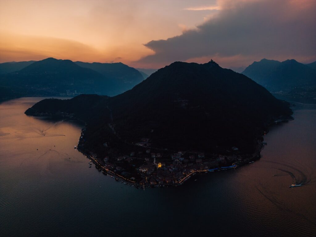 Sluimerende avondlucht boven een kaap met verlichte kustplaats in Sicilië