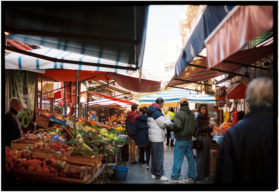 Druk Siciliaans voedselmarktpad met klanten bij kleurrijke groentekraampjes