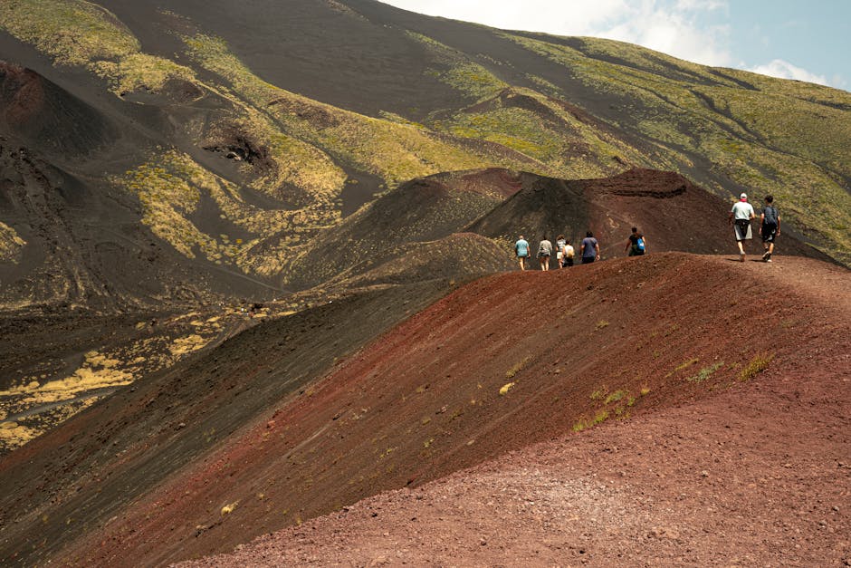 Hikers walking along red volcanic ridge on Mount Etna, Sicily
