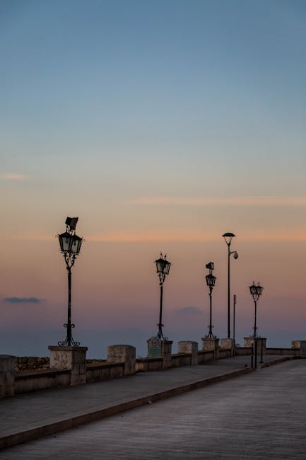 Ornate lamp posts lining a seaside promenade at dusk in Sicily