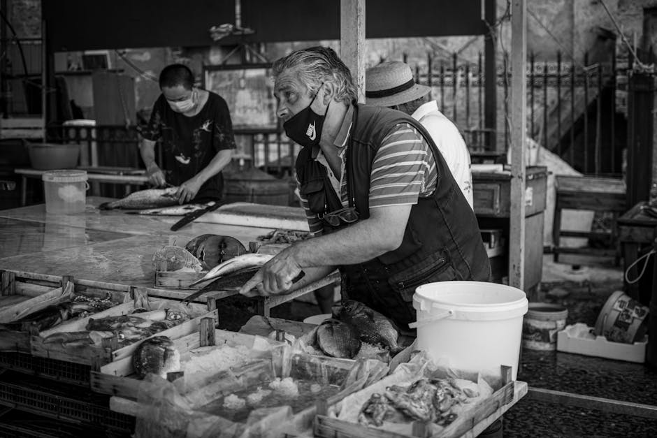 Masked fishmonger preparing fresh fish at a Sicilian market stall