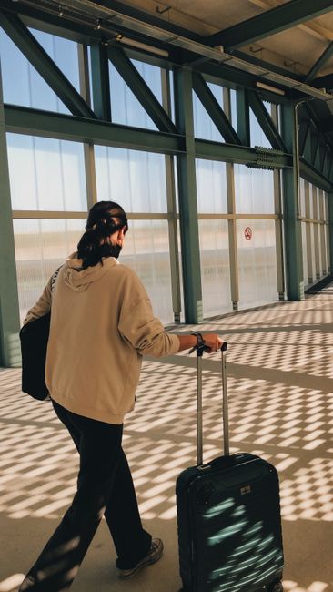 Traveler pulling suitcase through light-filled terminal before Sicily trip