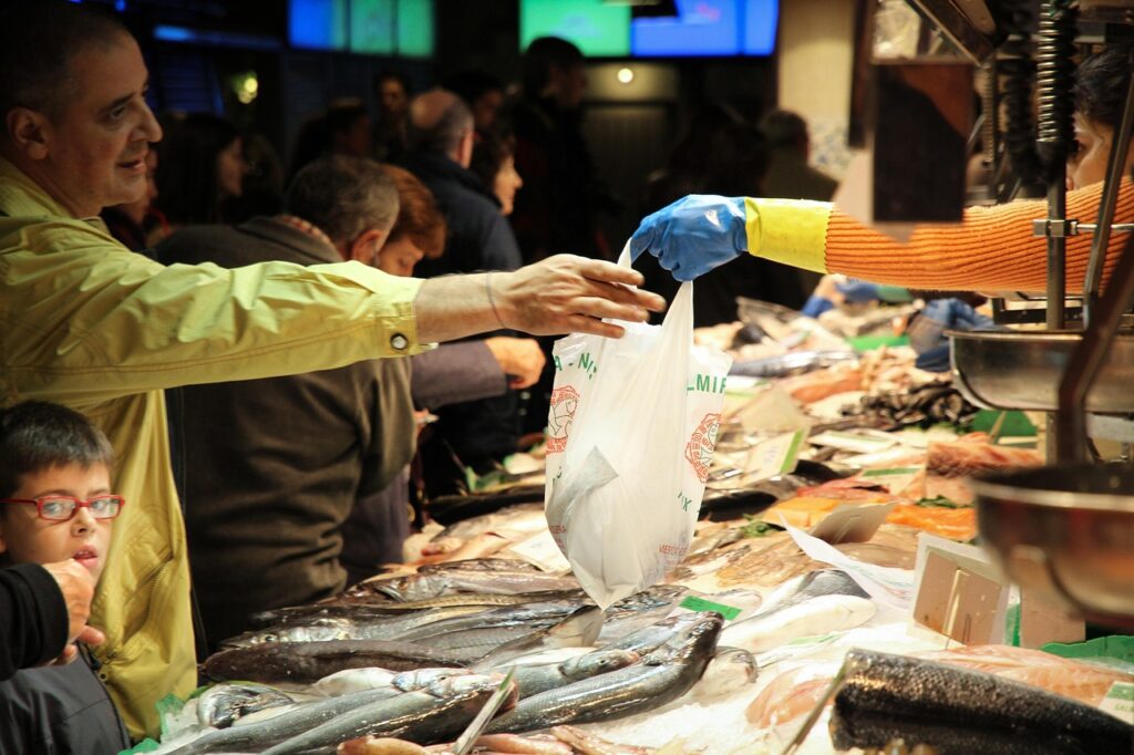 Customer receiving a bag of fresh fish at a Sicilian market counter