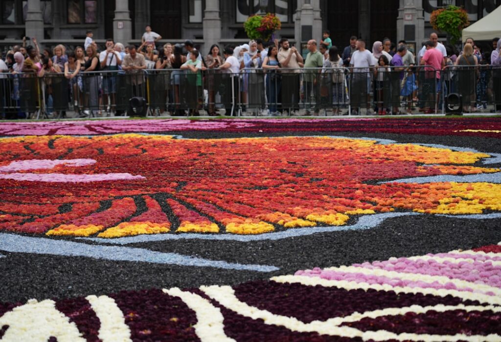 Tapis floral coloré d'infiorata sicilienne, foule admirant l'œuvre