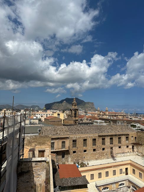 Sicilian rooftops and church bell tower with mountain and cloudy sky