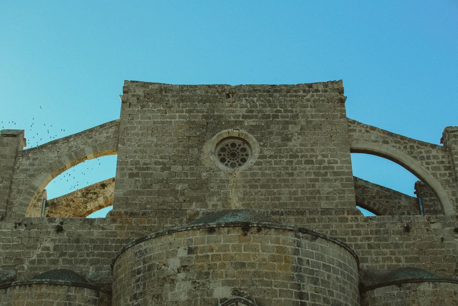 Weathered stone basilica ruins with circular rose window in Sicily