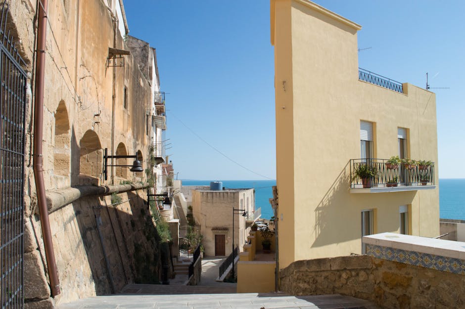 Narrow Sicilian alley between ochre buildings opening to the sea