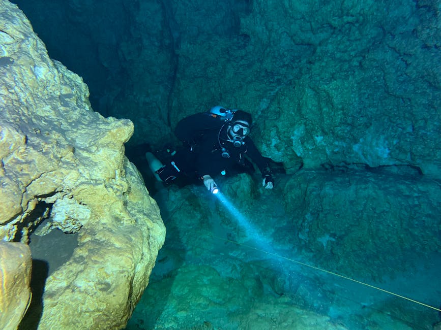 Subacqueo con torcia esplora grotta sottomarina nella riserva di Plemmirio, Sicilia